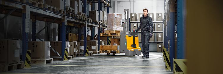 Magazynier przewożący ładunek na wózku