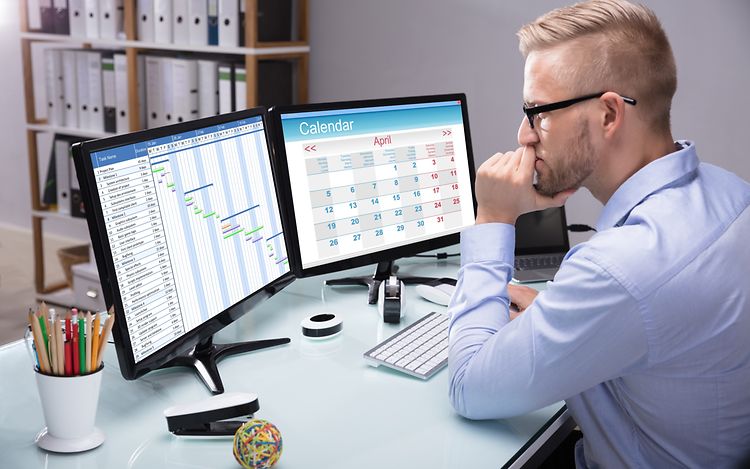 Businessman sitting in the office at his computer_[MAM-52778]