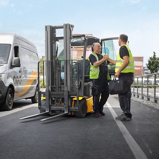 Två män hälsar framför en Jungheinrich motviktstruck.