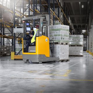 En förare transporterar gods med en Jungheinrich skjustativtruck på Werner & Mertz lager.