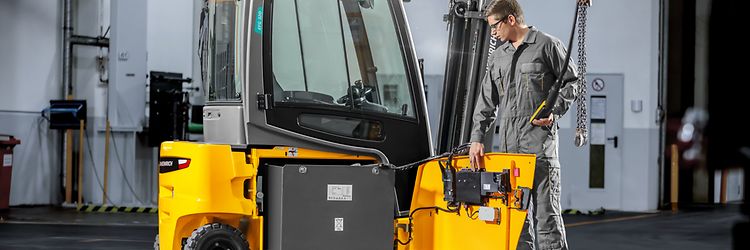 Man som står vid en Jungheinrich EFG motviktstruck med batteriluckan öppen.