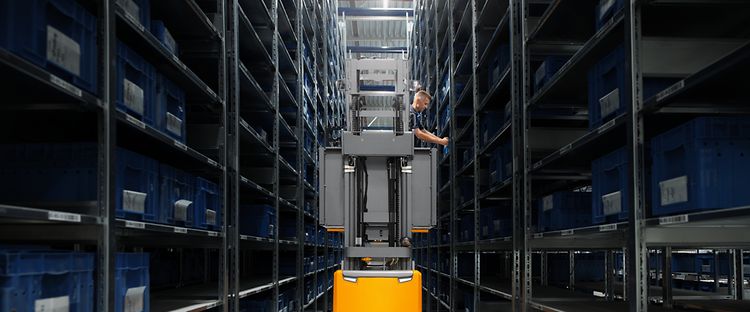 Man som plockar varor på ett lager i en Jungheinrich höglyftande plocktruck EKX 412s.