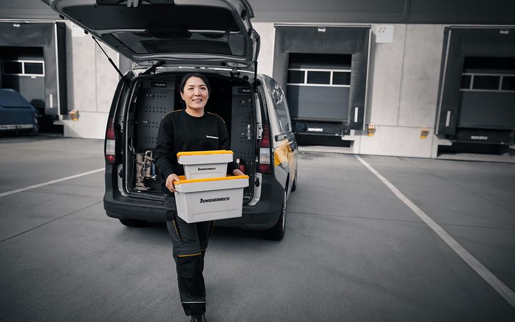 Jungheinrich tekniker framför en servicebil bärandes två servicelådor.
