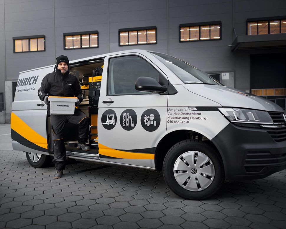 Jungheinrich servicetekniker framför en Jungheinrich servicebil med öppen dörr.
