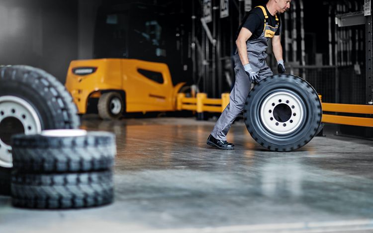 Jungheinrich verkstadsmedarbetare rullar ett däck i Jungheinrich verkstad.