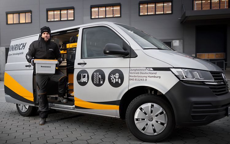 Jungheinrich servicetekniker framför en Jungheinrich servicebil med öppen dörr.