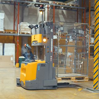 En man står bredvid en Jungheinrich AGV på DB Schenkers sorteringsanläggning i Borås.