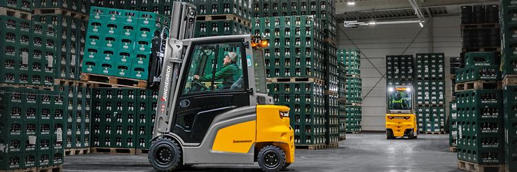 Jungheinrich el truck EFG 430 transporterer en palle med drikkekasser i et lager.