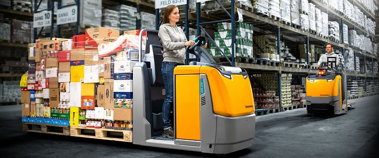  Jungheinrich plukketruck ECE 225, lastet med varer, kører rundt på et lager.