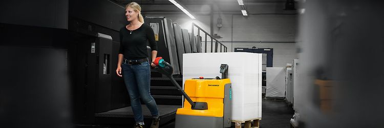 Kvinde bruger brugt palleløfter på lager