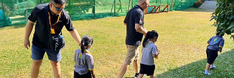 Foto von zwei Jungheinrich Mitarbeitern bei Aktionen mit drei Kindern auf einer grünen Wiese.