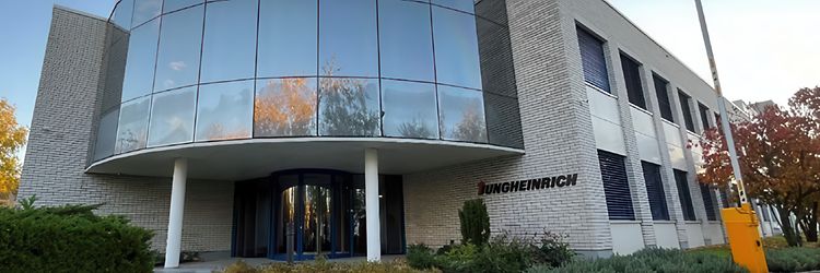 Photo of the modern Jungheinrich building near Budapest with a large curved glass facade.