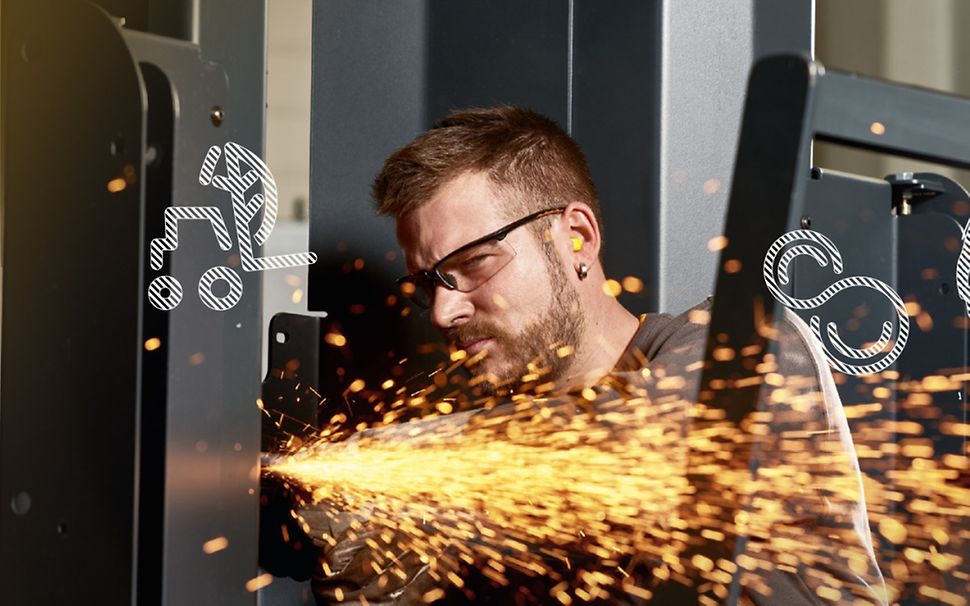 Foto von einem Jungheinrich Mitarbeiter mit Schutzbrille, der Stahl an einem Hubmast flext. Funken sprühen.