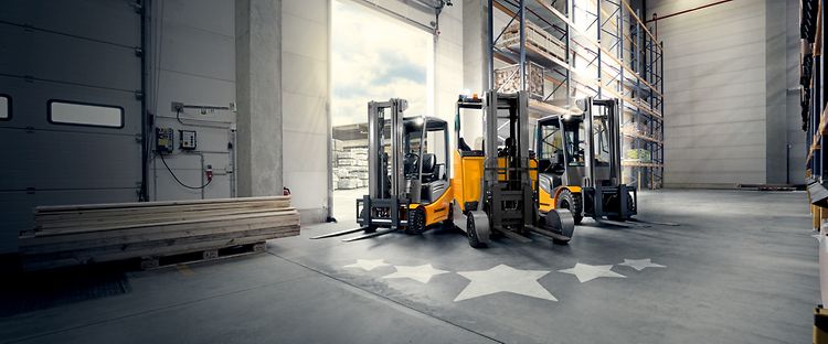 Photo shows Jungheinrich's overhauled JUNGSTAR trucks. Stars are depicted on the floor in front of the trucks.