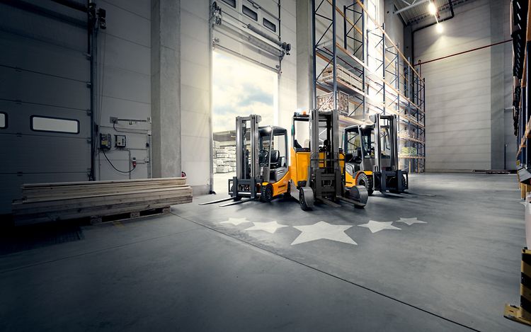 Photo shows Jungheinrich's overhauled JUNGSTAR trucks. Stars are depicted on the floor in front of the trucks.