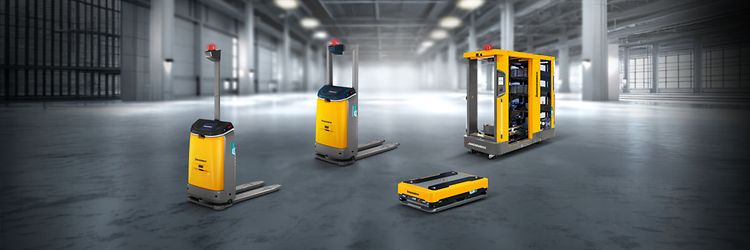 Four Jungheinrich autonomous vehicles are parked in a large, empty warehouse.