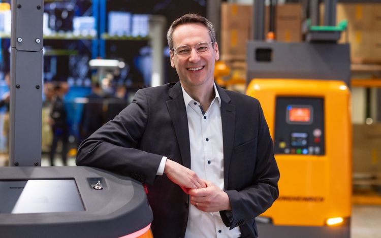 Dr. Tobias Harzer lehnt an einem Fahrzeug und lächelt in die Kamera.
