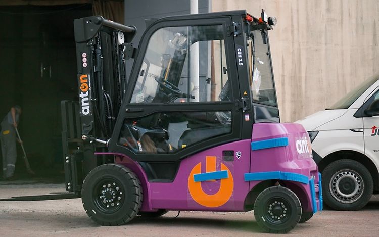 In the centre of the picture stands a purple forklift truck, an AntOn by Jungheinrich.