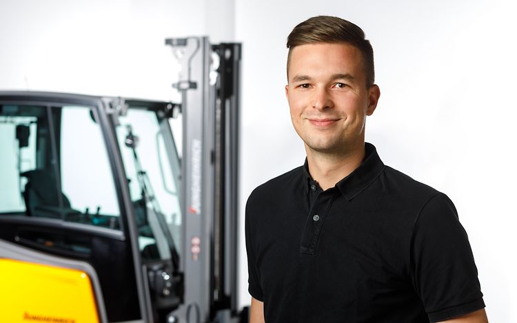 Ludwig Herzog is standing in front of a Jungheinrich forklift and smiling at the camera.