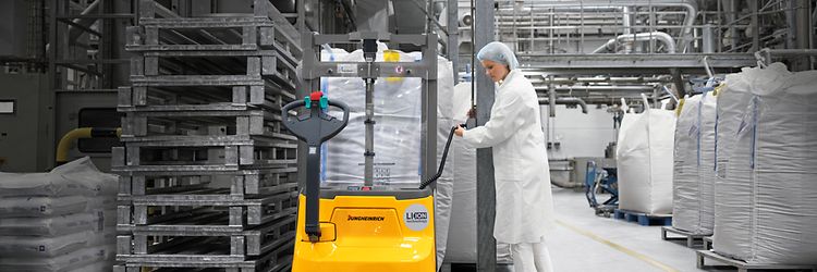 Kobieta podłącza prostownik wózka paletowego do prądu – jungheinrich.pl