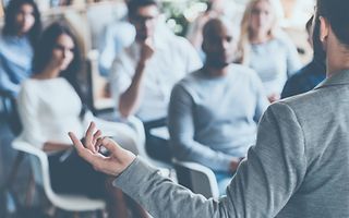 Business coach gives a lecture in front of his audience_[MAM-51056] (1)