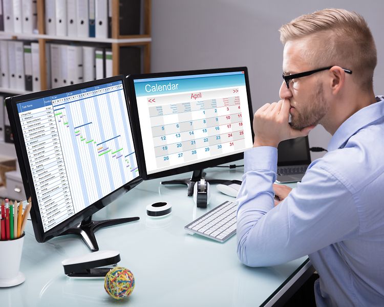 Businessman sitting in the office at his computer_[MAM-52778]